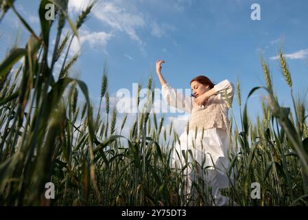 Eine junge Frau in weiß tanzt und berührt Weizen auf einem Feld A Stockfoto