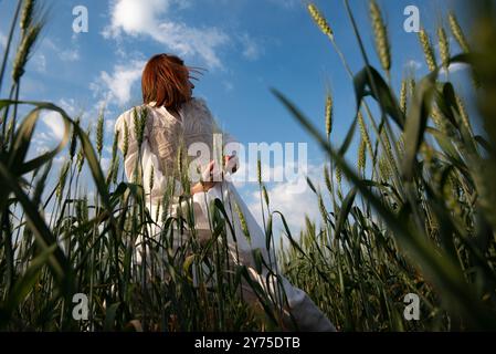 Eine junge Frau in weiß tanzt und berührt Weizen auf einem Feld A Stockfoto