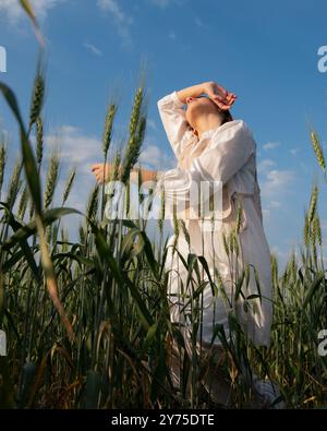 Eine junge Frau in weiß tanzt und berührt Weizen auf einem Feld A Stockfoto