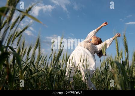 Eine junge Frau, die weiß tanzt und in den Himmel blickt Stockfoto