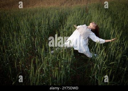 Eine junge Frau in weiß tanzt und schaut in den Himmel Stockfoto