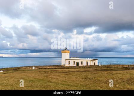 John o'Groats, Schottland, Vereinigtes Königreich - 3. Dezember 2023: Weißer Leuchtturm am Duncansby Head, Felder und Ozean unter bewölktem Winterhimmel. Leuchtfeuer in Schottland, Th Stockfoto