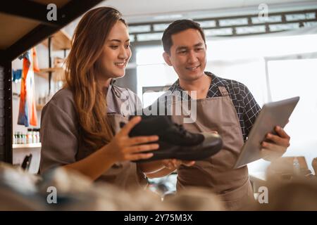 Weibliches Personal überprüft Sneakers im Regal mit männlichem Personal Stockfoto