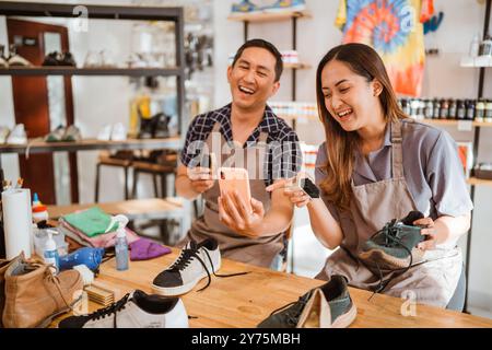 asiatische Arbeiter lachen über etwas am Telefon Stockfoto