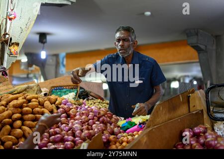 Port Louis, Mauritius . 25. Oktober 2023: Verkäufer, der Zwiebeln und Kartoffeln auf dem Zentralmarkt verkauft. Stockfoto