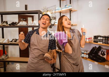 Arbeiter, die mit Schuhen in der Hand stehen, Reinigungswerkzeuge Stockfoto