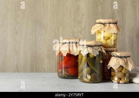 Verschiedene eingelegte Produkte in Gläsern auf grauem Tisch, Platz für Text Stockfoto