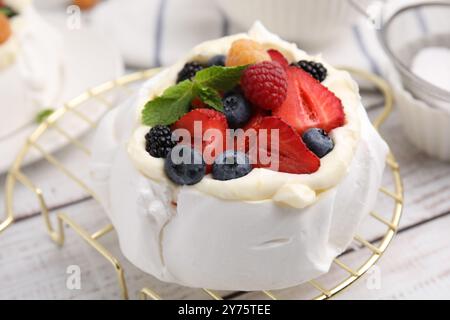 Pavlova Kuchen (Meringue Dessert) mit Schlagsahne, frischen Beeren und Minze auf weißem Holztisch, Nahaufnahme Stockfoto