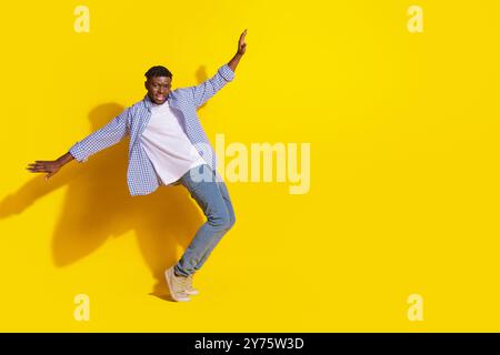 Foto eines jungen Models, der ein lässiges kariertes Hemd und Jeans trägt, der auf gelben Hintergründen hängt Stockfoto