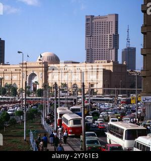 Tägliches Verkehrschaos auf der Meret Basha Straße mit Blick auf das Ägyptische Museum (Kuppel) und den Ramses Hotelturm in Kairo, nahe vom Midan al Tahrir Platz, Ägypten um 1987. Stockfoto