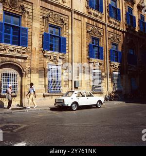 Ein weißes Auto parkt vor einem Stadthaus mit blauen Fensterläden in der Inselhauptsadt La Valletta auf der Insel Malta, um 1984. Stockfoto