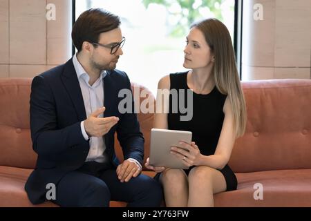 Zwei sehr beschäftigte Kollegen, die sich in der Lobby des Büros unterhalten Stockfoto