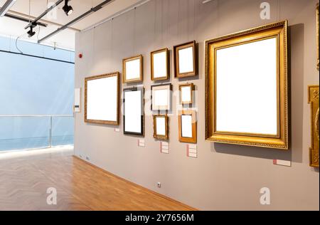 Viele leere leere, ausgeschnittene Weißgold-Bilderrahmen hängen an einer Wand in einem modernen Museum oder einer Kunstgalerie, viele Gemälde auf einem Stockfoto