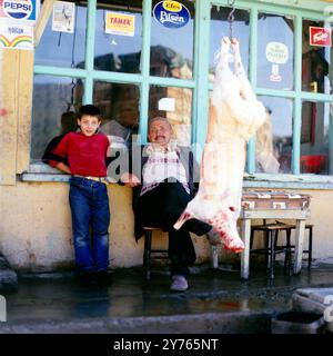 Ein Junge, ein Mann und ein geschlachtetes Tier vor einer Kneipe in einem Ort im Zigana-Pass (Zigana Gecidi) in der Provinz Trabzon oder Gümüshane (Gümüşhane) in Nordostanatolien, Türkei um 1988. Stockfoto