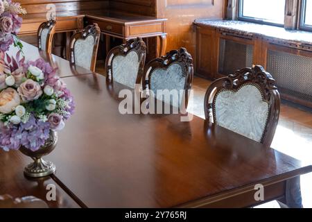 Altmodischer, antiker Holztisch mit 5 Stühlen und Blumen auf der Oberseite, Nahaufnahme Details, niemand, generisches altmodisches, luxuriöses Interieur im Retro-Stil Stockfoto