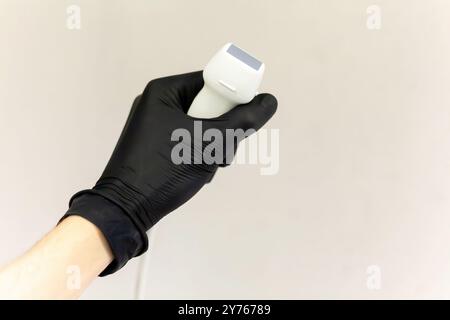 Nahaufnahme einer Ärztin Hand, die einen schwarzen sterilen Latexhandschuh trägt, der eine moderne Ultraschallsonde auf grauem Hintergrund hält, Mann, eine Person. Ultraschall Stockfoto
