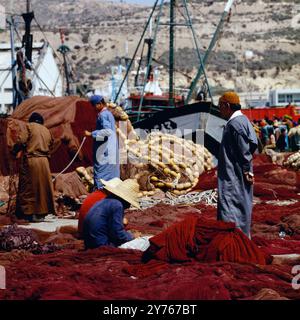 Aufseher und Arbeiter beim Knüpfen von Netzen im Hafen von Agadir, Marokko um 1985. Stockfoto