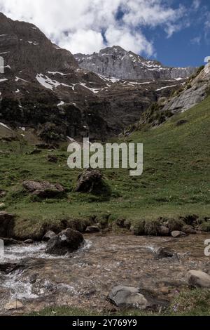 Majestätische Berglandschaft mit einem klaren Bach, der durch ein üppiges grünes Tal fließt Stockfoto