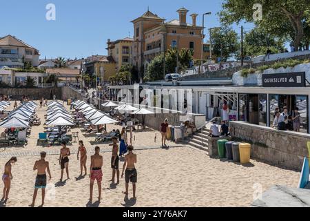 Viele Badende im Praia da Ribeira de Cascais voller weißer quadratischer Sonnenschirme in der portugiesischen Stadt Cascaes, im Bezirk Lissabon, Portugal. Stockfoto