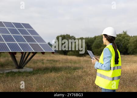 Solarenergie-Ingenieur oder -Techniker, der eine Solarpaneel-Struktur in einem ländlichen Feld inspiziert Stockfoto