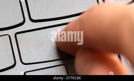 Mann, der eine leere Taste auf einer modernen Laptop-Tastatur drückt, eine Person. Fingerklick auf eine leere Taste auf einer einfachen Computertastatur, Taste ohne Etikett, cl Stockfoto