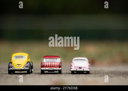 Woodbridge, New Jersey - 27. September 2024: Drei Spielzeugautos aus Druckguss, ein Volkswagen Beetle 1976, ein Chevy Nomad 1955 und ein Cadillac 1953, stehen auf dem Parkplatz Stockfoto