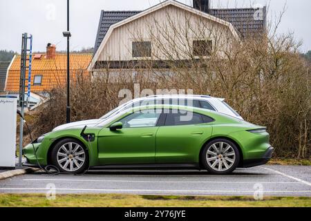 Mölndal, Schweden - 29. Januar 2023: Umweltfreundlicher elektrischer Porsche Taycan lädt auf einem Parkplatz auf Stockfoto