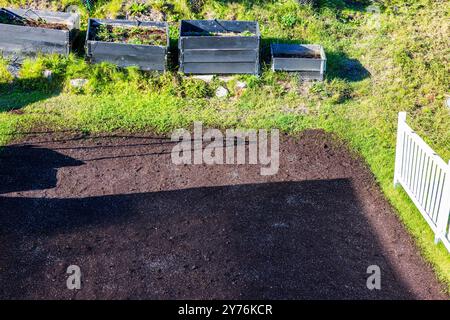 Blick von oben auf den Garten mit vorbereitetem Boden und erhöhten Gartenbeeten, bereit zum Pflanzen, im grünen Außenbereich. Schweden. Stockfoto