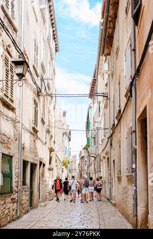 Rovinj Kroatien 27. August 2024 Besucher schlendern entlang einer malerischen Kopfsteinpflasterstraße, die von historischen Gebäuden und lebhaften Farben gesäumt ist und sich in der warmen Sonne sonnt Stockfoto