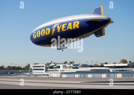 Der legendäre Goodyear Blimp, ein Symbol der Luftschifffahrt, fliegt anmutig über einem Flughafen. Gefangen vor einem klaren Himmel mit Blick auf die Hangars unten Stockfoto