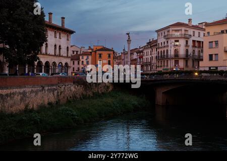 Vicenza, Italien - 13. September 2024: Ein Blick bei Sonnenuntergang auf einen ruhigen Fluss in Vicenza, mit dem berühmten Durchbruch des Porta Pia Monuments, Säule ri Stockfoto