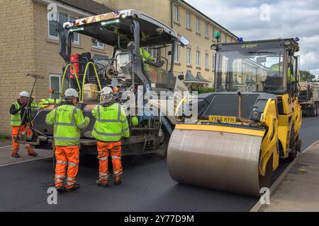 Ein Team von Arbeitern, die schwere Maschinen bedienen, um eine Wohnstraße in Wiltshire wiederzubeleben. Stockfoto