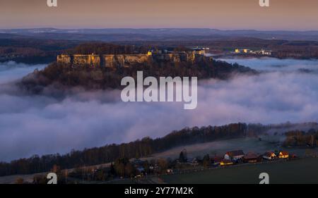 Hoch oben über dem Fluss Elbthront die Festung Königstein. Jahrhunderte als uneinnehmbar geltend, erscheint die sagenumwobene Burg im dichten Nebel. Stockfoto