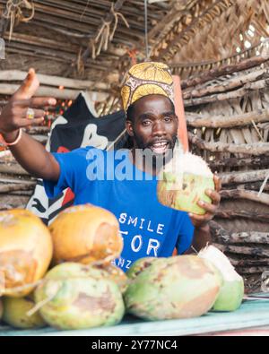 Sansibar, Tansania - 14. Februar 2022: Glücklicher afrikanischer Mann, der Kokosnüsse verkauft. Stockfoto