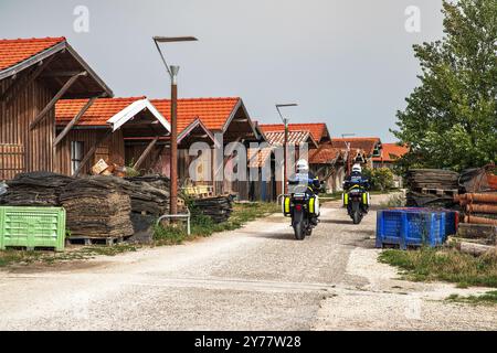 Zwei Kommunalpolizisten-Motorradfahrer mit französischer Schrift „Kommunalpolizei“ fahren durch die für Austernbauern typischen Holzhütten Stockfoto