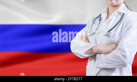 Doktor mit Stethoskop auf russischer Flagge. Russisches Gesundheits- und Pflegekonzept. Doktor mit gekreuzten Armen auf der Flagge der Russischen Föderation Stockfoto