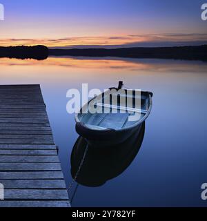 Ruhiger See mit Steg und Ruderboot nach Sonnenuntergang in der Abenddämmerung, großer Lychensee, Lychen, Brandenburg, Deutschland, Europa Stockfoto