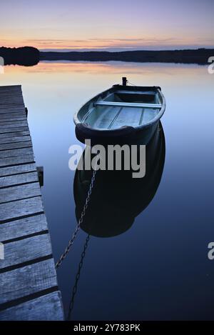 Ruhiger See mit Steg und Ruderboot nach Sonnenuntergang in der Abenddämmerung, großer Lychensee, Lychen, Brandenburg, Deutschland, Europa Stockfoto