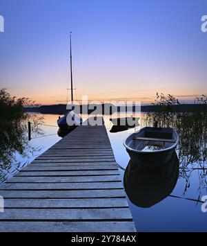 Ruhiger See mit Steg und Booten nach Sonnenuntergang in der Abenddämmerung, großer Lychensee, Lychen, Brandenburg, Deutschland, Europa Stockfoto