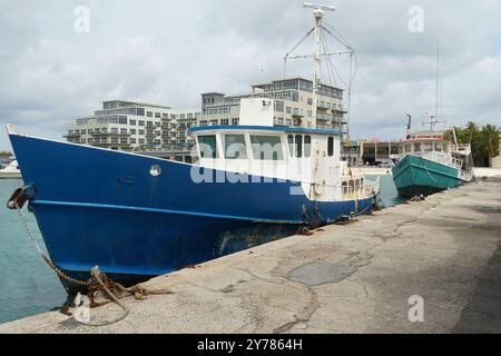 Fischerboot mit blauem Rumpf vor dem modernen luxuriösen Hotel in der Meeresbucht von Oranjestad, einer der Karibikinsel Aruba. Stockfoto