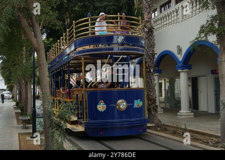 Downtown Trolley oder Straßenbahnen voller Touristen vorbei an engen Straßen mit farbenfrohen Gebäuden und Palmen auf der Karibikinsel Aruba in Oranjestad. Stockfoto