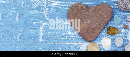 Meereskiesel und Muscheln auf dem Tisch. Eine Pyramide aus Meeressteinen auf blauem Hintergrund Stockfoto