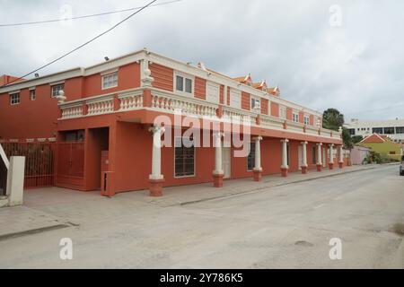 Rotes Gebäude im Kolonialstil im Downtown District an einer engen, von Palmen gesäumten Straße in Oranjestad, Aruba. Stockfoto