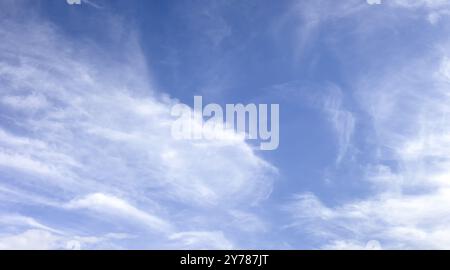 Panorama von weißen, weichen, verschwommenen Wolken auf einem Hintergrund blauen Himmels. Leichte Wolken an einem hellen sonnigen Sommertag. Der Wind bläst kleine Wolken über die s Stockfoto