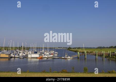 Ein geschäftiger Bootshafen mit vielen Yachten und Booten auf dem ruhigen Fluss unter klarem Himmel, Greetsiel, Ostfriesland, Deutschland, Europa Stockfoto