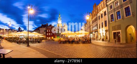 Ein Panoramablick am Abend auf den Altstädter Ring von Posen in Polen, der die beleuchteten historischen Gebäude, die lebhaften Cafés im Freien und das geschäftige Treiben in der Stadt erfasst Stockfoto