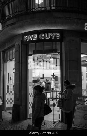 Schwarzweiß-Foto von Personen, die während der covid-Pandemie vor dem Restaurant stehen und auf Bestellung warten Stockfoto