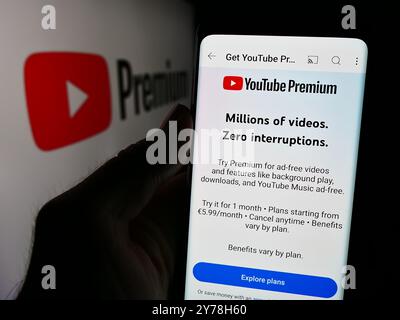 In dieser Fotoabbildung hält eine Person ein Smartphone mit der Webseite des Video-Streaming-Abonnementdienstes YouTube Premium vor dem Logo. Stockfoto