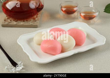 Rosa und weiße Songpyeon, halbmondförmiger koreanischer Reiskuchen. Serviert auf dem weißen Teller. Traditionelles koreanisches Essen am Neujahrstag Stockfoto