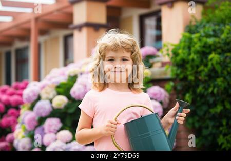 Kind Junge wässern Pflanzen im Garten mit Gießkannen. Die Welt grün machen. Sommerlandwirtschaft. Stockfoto